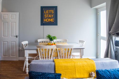 a dining room with a table and chairs with yellow blankets at Blackpool Abode - Beach Garden Apartment in Blackpool