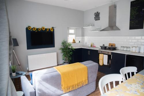 a kitchen with a couch and a table with a yellow towel at Blackpool Abode - Beach Garden Apartment in Blackpool