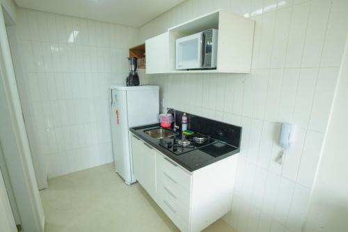 a white kitchen with a sink and a refrigerator at Porto Star Prime By AFT in Porto De Galinhas
