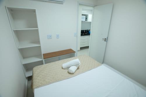 a small white room with a bed and a mirror at Porto Star Prime By AFT in Porto De Galinhas