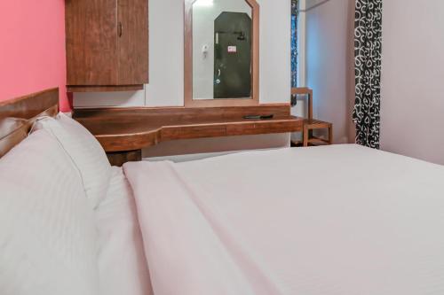 a bedroom with a white bed and a mirror at OYO Hotel Kota Lodge in Coimbatore