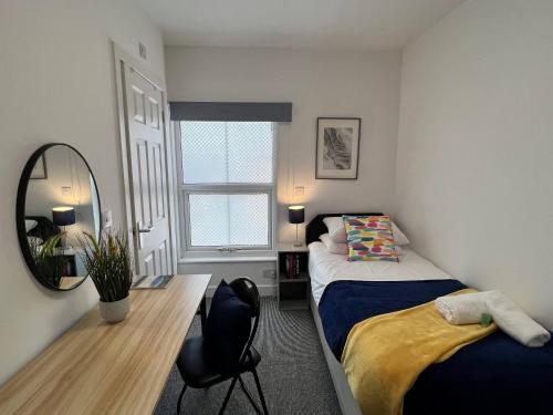 a small bedroom with two beds and a mirror at Stay @ The Wellington, Burton On Trent in Burton upon Trent