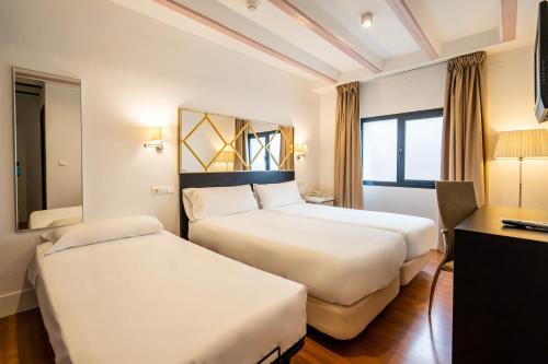a hotel room with two beds and a desk at YIT El Postigo in Úbeda