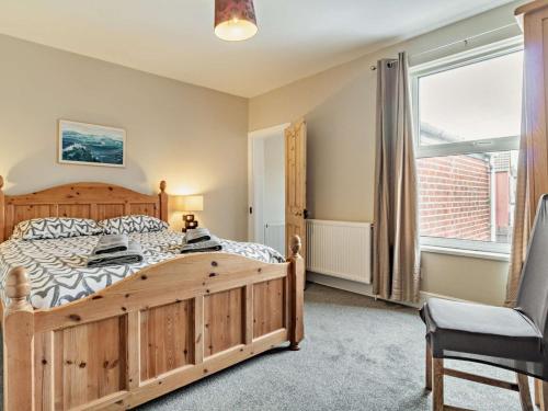 een slaapkamer met een houten bed en een groot raam bij Harbour Walk in Brightlingsea