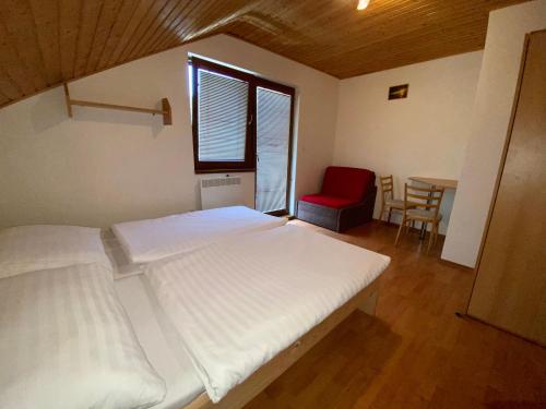 a bedroom with two beds and a table with a red chair at Apartmány Alma in Vyhne