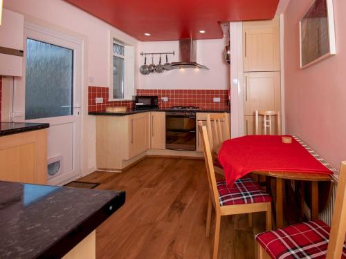 uma cozinha com uma mesa com uma toalha de mesa vermelha em Pass the Keys Private Entrance GF 2 bed flat near Renfrew Centre em Renfrew