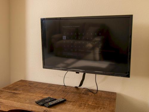 a flat screen tv hanging on a wall with two remote controls at Pass the Keys Private Entrance GF 2 bed flat near Renfrew Centre in Renfrew