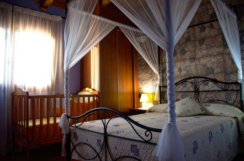 1 dormitorio con cama con dosel y cortinas blancas en casa oliva la bodegueta en Abiego