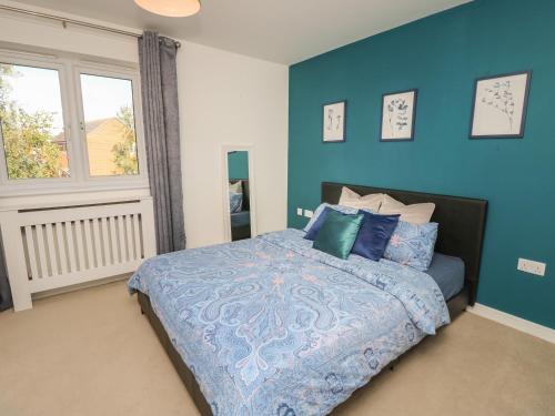 a bedroom with a bed with blue walls and a window at 19 Windsurfing Place in South Hayling