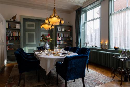 een eetkamer met een tafel, stoelen en een kroonluchter bij De Jonge Barones in Beetsterzwaag