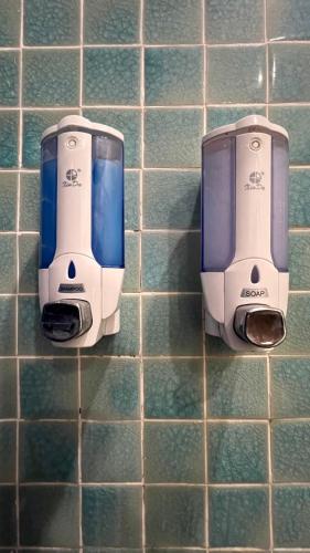 two soap dispensers on a tiled bathroom wall at Drift Backpackers Hostel in Hanoi