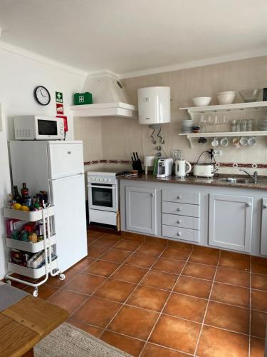 a kitchen with white appliances and a brown tile floor at The Doll’s House in Tavira