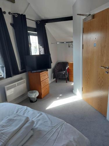 1 dormitorio con 1 cama, TV y silla en EBBERLEY ARMS en Barnstaple