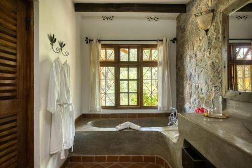 baño con bañera grande y pared de piedra. en Rivertrees Country Inn en Usa River