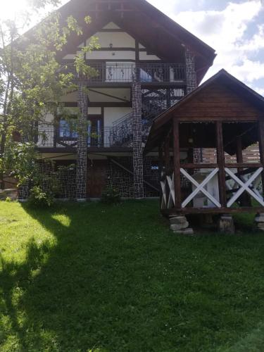 Cette grande maison dispose d'une terrasse couverte et d'une pelouse. dans l'établissement Садиба АнноМарі - відпочинок в Карпатах котедж Яремче, à Yaremtche