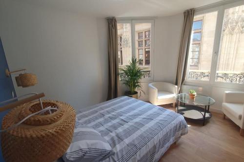 ein Schlafzimmer mit einem Bett und einem Stuhl und Fenstern in der Unterkunft Appartement palais de justice in Rouen