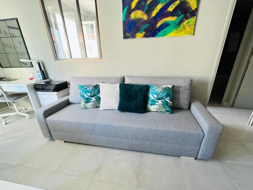 un sofá con almohadas en la sala de estar. en Nice west cosy flat balcony, near airport, train, beach, public transport, supermarket, comfortable and well equipped en Niza