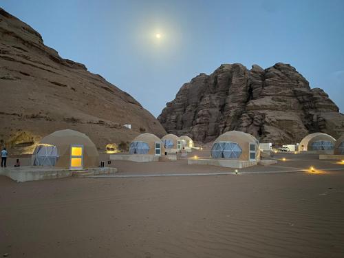 a group of white domes in front of a mountain at Rum Armony camp in Wadi Rum