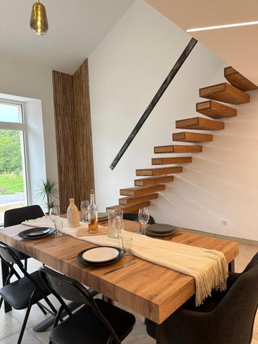 a dining room with a wooden table and a staircase at Bulles de Nature 