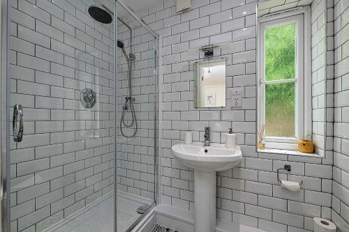 a white bathroom with a sink and a window at Finest Retreats - Y Lle Hapus in Tenby
