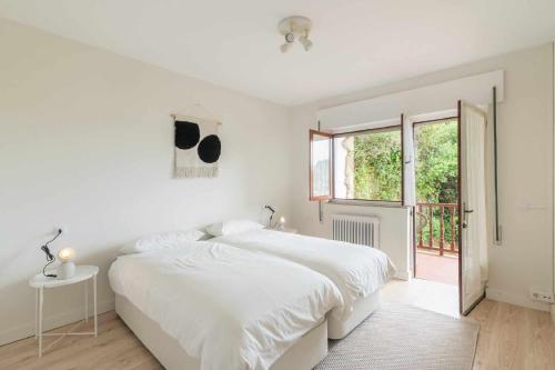 a white bedroom with a white bed and a window at Villa Vacacional Toró Playa in Llanes