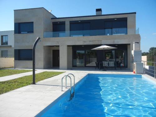 una casa con piscina frente a un edificio en Chalet de diseño moderno en Sanxenxo, en Sanxenxo