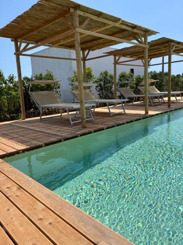 a swimming pool with a wooden deck and a gazebo at Volito Rural Experience in Patù