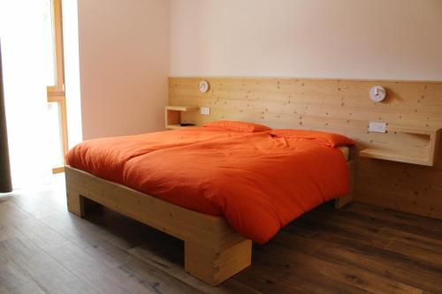 1 dormitorio con cama de madera y edredón de naranja en B&B Terre Alte, en Ceresè