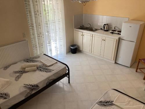 a room with a bed and a kitchen with a refrigerator at Polyxenis Rooms in Lygia