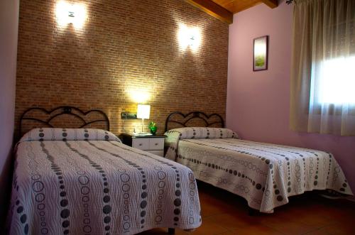 a bedroom with two beds and a brick wall at casa oliva la bodegueta in Abiego