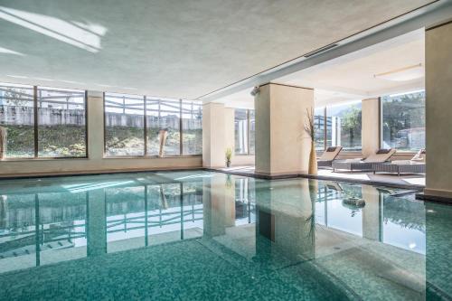 a swimming pool in a building with glass windows at Residence Anda in Pozza di Fassa