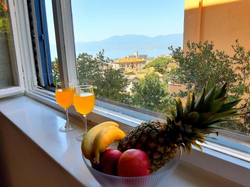 a bowl of fruit and two glasses of orange juice on a window sill at Amarena Apartment in Rijeka