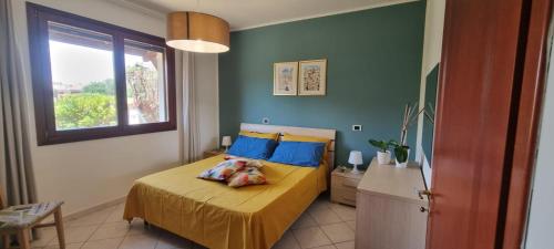 um quarto com uma cama com almofadas azuis e uma janela em Le case del sole em Capoterra