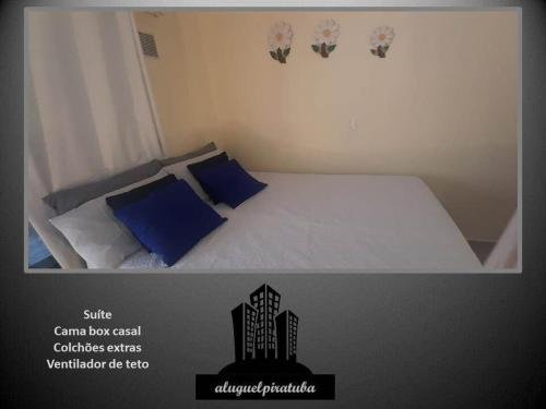 ein Schlafzimmer mit einem weißen Bett mit blauen Kissen in der Unterkunft Incrível localização 102, apenas 4 min do Parque in Piratuba