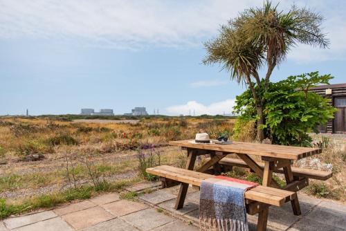 a wooden picnic table with a tree in a field at The Watch Tower by Bloom Stays in Dungeness