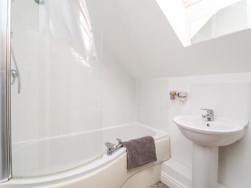 a white bathroom with a shower and a sink at 8 Pottergate Mews in Helmsley