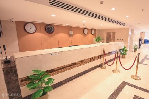 una hall con orologi appesi al muro e un bancone della reception di Nawazi Towers Hotel a La Mecca