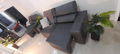 a living room with a leather couch and two plants at Aconchegante apto 104 fica 5 min do Parque Termal in Piratuba
