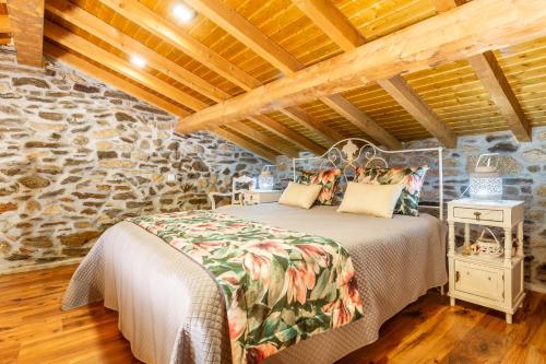 - une chambre avec un lit et un mur en pierre dans l'établissement Casa do Feitor - Douro - Quinta da Cabrida, à Sendim