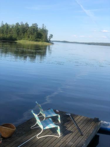 a pair of chairs sitting on a dock on a lake at Herrestad Bed & Guestroom in Värnamo