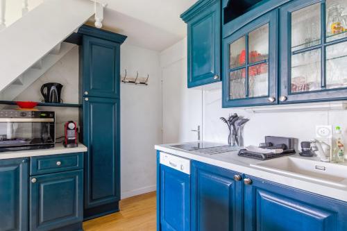 - une cuisine avec des placards bleus et un évier dans l'établissement Beautiful duplex with balcony in Cabourg - Welkeys, à Cabourg
