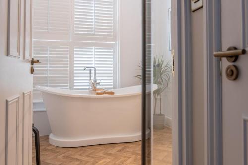a white bath tub in a bathroom with a window at The Crown Pub and Hotel in Manningtree