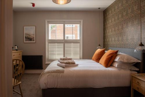 1 dormitorio con 1 cama con almohadas de color naranja y ventana en The Crown Pub and Hotel, en Manningtree