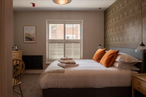 a bedroom with a bed with orange pillows and a window at The Crown Pub and Hotel in Manningtree