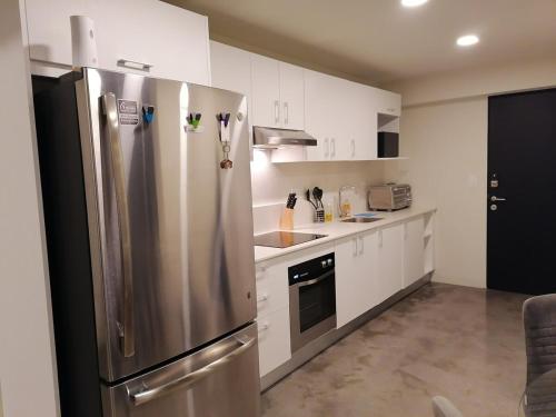 a kitchen with a stainless steel refrigerator and white cabinets at Urbn Moras in San José