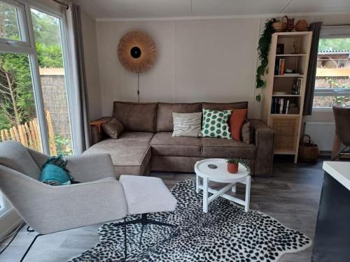 a living room with a couch and a table at Boshuis met grote tuin I Vakantiepark met Zwembad in Hoenderloo