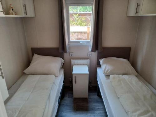 two beds in a small room with a window at Boshuis met grote tuin I Vakantiepark met Zwembad in Hoenderloo