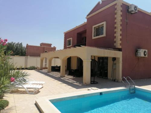 a house with a swimming pool in front of it at Villa Maria Paradise in Giza