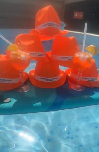 un groupe de chapeaux orange et de lunettes sur une table dans l'établissement Résidence La Cigale du Désire Séjour chez l habitant, à Riez