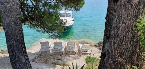 a group of chairs and a boat in the water at Dolce Villa, votre maison en front de mer in Lumbarda